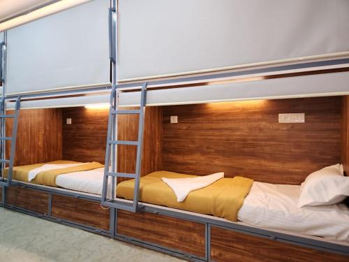 Ce lit se trouve dans un dortoir doté de 2 lits superposés et de murs en bois. dans l'établissement SAHIL AC DORMITORY, à Navi Mumbai