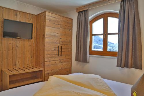a bedroom with a bed and a tv and a window at Ferien Bauernhof Maurachhof in Sankt Johann im Pongau