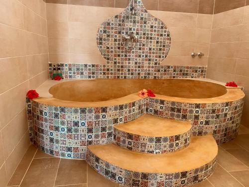 a bathroom with a tub with tiles on the wall at Nungwi Garden Boutique Hotel in Nungwi