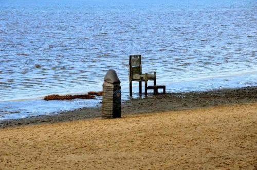 uma cadeira sentada na praia junto à água em Ferienhaus Förster, FeWo Vermittlung Nordsee em Dangast