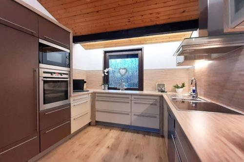 a kitchen with stainless steel appliances and a window at Ferienhaus LENA im Sauerland direkt am Hennesee in Meschede