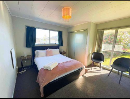 a bedroom with a bed and two chairs and a window at Mountain Top kiwi star holiday home in Rotorua