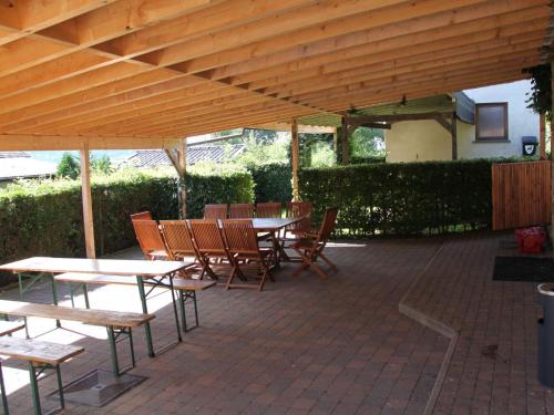 un patio con mesas y sillas bajo un techo de madera en Spacious Apartment in Ondenval with Terrace, en Waimes