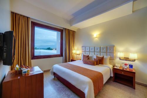 ein Hotelzimmer mit einem großen Bett und einem Fenster in der Unterkunft Royal Sarovar Portico Siliguri in Shiliguri
