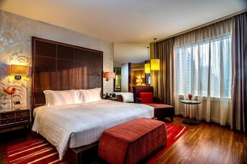 曼谷曼谷阿索克希尔顿酒店 - Hilton Bangkok Grande Asoke的配有一张大床和一把椅子的酒店房间