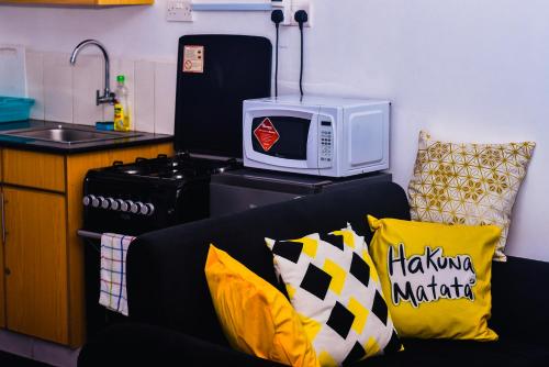 a kitchen with a microwave and a couch with pillows at Lynne’s Cozy studio in Nairobi