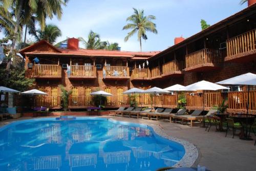 a resort with a swimming pool and tables and umbrellas at Sea Breeze Village, Baga Goa in Calangute