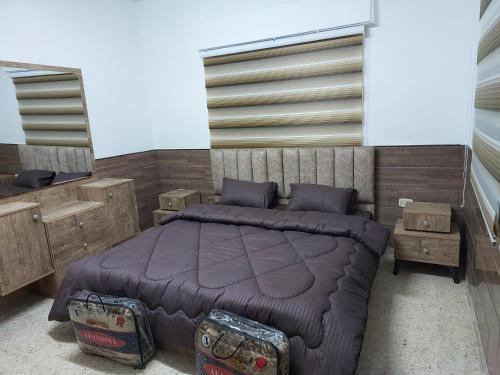 1 dormitorio con cama morada y algunos muebles de madera en Cozy Home en Amán
