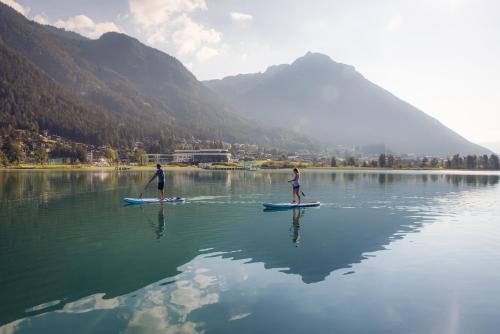 two people on paddle boards in the water at NOVA Moments Boutique Hotel in Pertisau