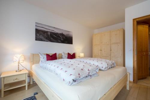 a bedroom with a large white bed with red pillows at Ferienwohnung Bacco in Oberstdorf