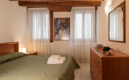 sypialnia z zielonym łóżkiem, komodą i oknami w obiekcie Hotel Commercio & Pellegrino w Wenecji