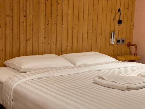 a large white bed with a wooden wall at Rock Forest in Sattahip