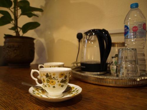eine Kaffeetasse und Untertasse auf einem Tisch mit einem Wasserkocher in der Unterkunft Painters at the Angel in Sudbury