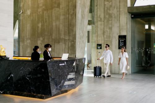 a group of people walking in a lobby with a counter at The Signature Hotel Airport in Hat Yai