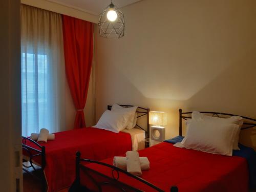 1 dormitorio con 2 camas con sábanas rojas y ventana en Elegante apartamento centrale, en Tríkala