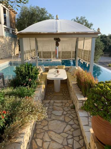 una mesa en un cenador junto a una piscina en Opera House Paxos en Gaios