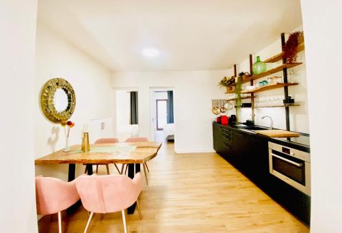 uma cozinha com uma mesa de madeira e cadeiras cor-de-rosa em Hotel Apartment with 2-en suite Bedrooms em Palma de Maiorca