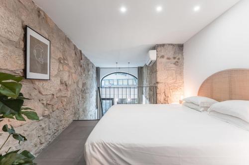 a bedroom with a white bed and a stone wall at GuestReady - Casa da Alegria 8 in Porto