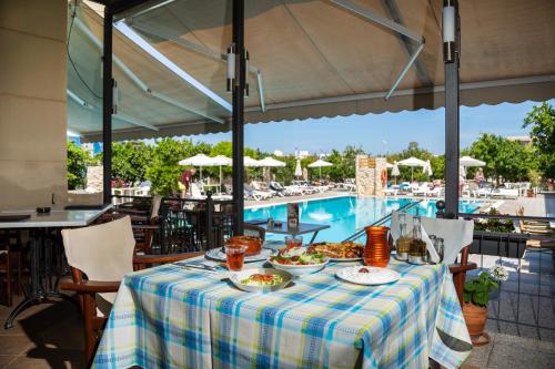 uma mesa com comida ao lado de uma piscina em Ilyssion Holidays Hotel em Ialyssos