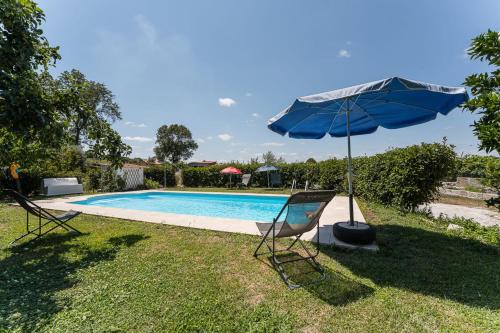a blue umbrella and chairs next to a swimming pool at GuestReady - Seven Farm in Mangualde