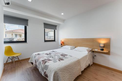 a bedroom with a large bed and a yellow chair at GuestReady - Seven Farm in Mangualde