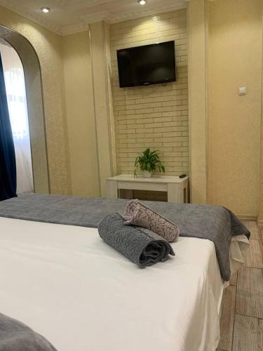 Schlafzimmer mit einem Bett und einem TV an der Wand in der Unterkunft LUX in Schymkent