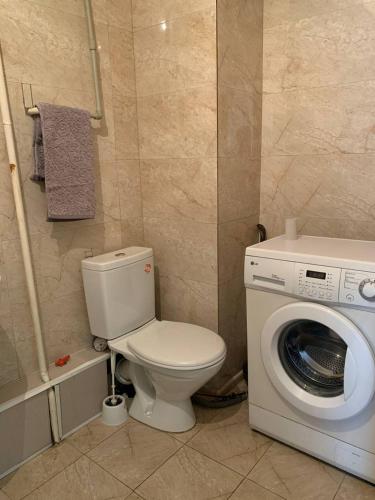 ein Badezimmer mit einem WC und einer Waschmaschine in der Unterkunft LUX in Schymkent