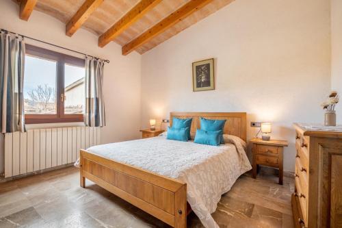 a bedroom with a bed with blue pillows and a window at Can Jaume in Pollença