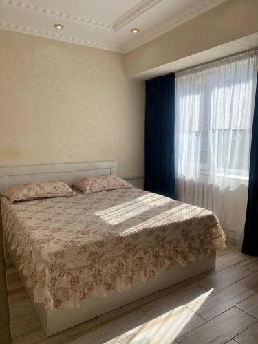 Schlafzimmer mit einem Bett und einem Fenster in der Unterkunft LUX in Schymkent