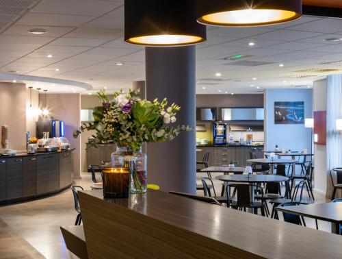 un restaurant avec des tables et un vase de fleurs sur un comptoir dans l'établissement Escale Oceania Pornichet La Baule, à Pornichet