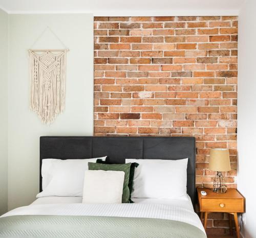 a bedroom with a brick wall and a bed at Bohema Place - Metro Szwedzka Apartment in Warsaw