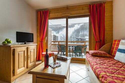 Il comprend un salon avec un canapé, une télévision et un balcon. dans l'établissement Lagrange Vacances Le Hameau du Rocher Blanc, à Saint-Chaffrey