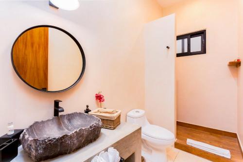 ein Badezimmer mit einem Waschbecken, einem WC und einem Spiegel in der Unterkunft 3 BD between ocean and downtown with amenities - Aldea Zama in Tulum