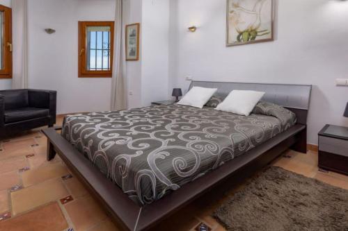 een groot bed in een kamer met een stoel bij Villa Ventura 8 Pers in Pego