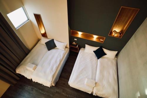 two beds in a hotel room with white sheets at Waiting Homestay in Taitung City