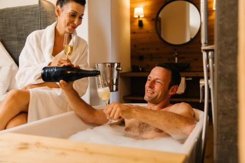 a woman is pouring a glass of wine in a bath tub at Unternberg Hof Ruhpolding in Ruhpolding