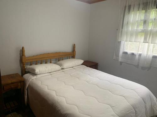 a white bed in a bedroom with a window at Cantinho do Sussego 2 in Campos do Jordão