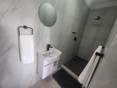 a white bathroom with a sink and a mirror at Gateway@134 Guesthouse in Vryheid