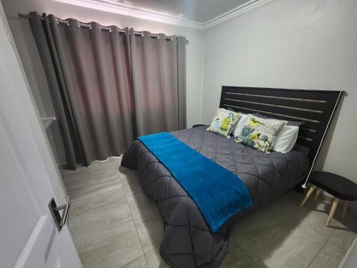 um quarto com uma cama com um cobertor azul em Gateway@134 Guesthouse em Vryheid