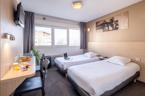 a hotel room with two beds and a desk with a laptop at Zenitude Hôtel-Résidences Les Hauts d'Annecy in Annecy