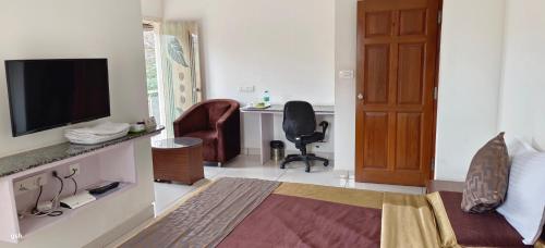 ein Wohnzimmer mit einem TV und einem Stuhl in der Unterkunft Sugamya Corner Guesthouse in Mysore