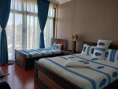 Blue Nile Guest House في لاليبيلا: سريرين في غرفة باللون الأزرق والأبيض