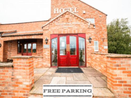 un edificio de ladrillo rojo con una señal de aparcamiento gratuita delante de él en OYO White Horse Lodge Hotel, East Thirsk, en Thirsk