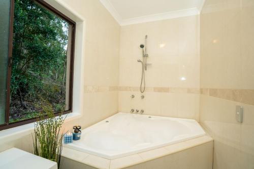 a white bath tub in a bathroom with a window at Bushland Retreat in Gold Coast