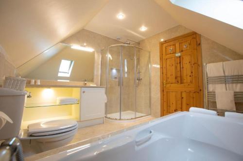 een badkamer met een douche, een toilet en een bad bij The Tides Ballybunion in Ballybunion