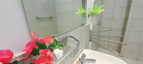 La salle de bains est pourvue d'un lavabo, d'un miroir et de fleurs. dans l'établissement Isuru Holiday Inn, à Matara