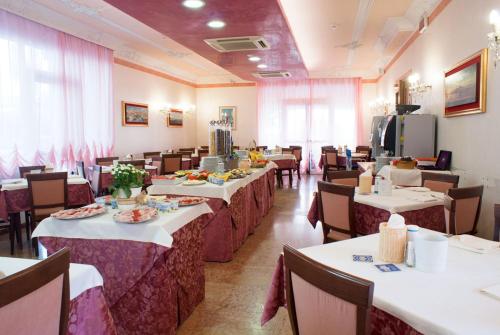 uma sala de jantar cheia de mesas e cadeiras com comida em Hotel Kennedy em Caorle