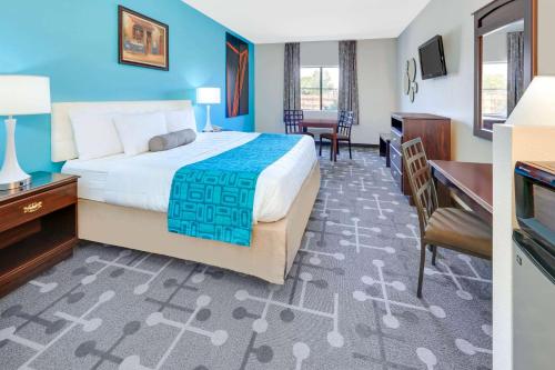 a hotel room with a bed and a desk and chairs at Howard Johnson by Wyndham Lubbock TX in Lubbock