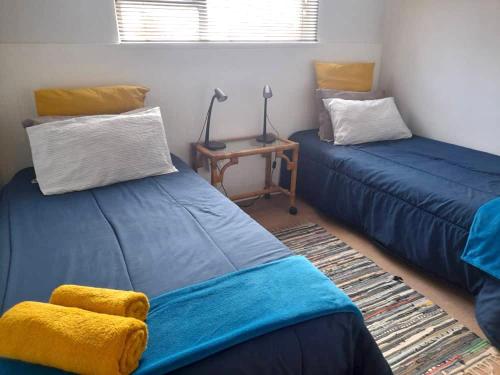 Habitación con 2 camas azules y mesa. en Beachfront Selfcatering, en Henties Bay