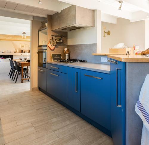 eine Küche mit blauen Schränken und einem Esszimmer in der Unterkunft AR MILIN - Magnifique moulin les pieds dans l'eau in Landunvez